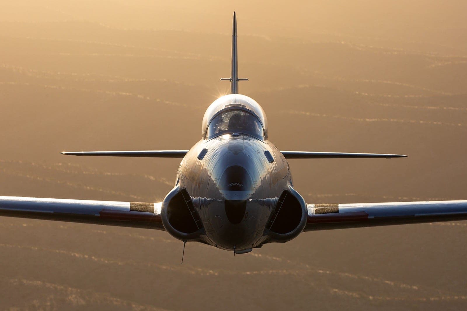 Head-on view of the T-33 in flight, golden hour, intakes catching the sun.