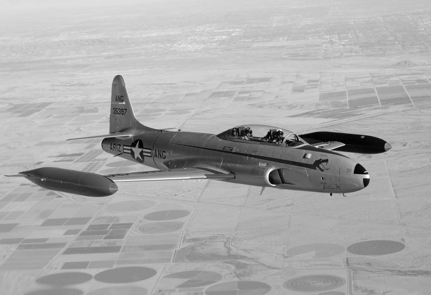 Black and white aerial photograph of the T-33 over Arizona farm fields, full Air National Guard markings visible.