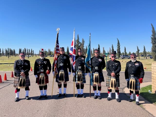 Seven members of the Scottish Honor Guard in kilts and glengarries, presenting the American, British, and band colors.