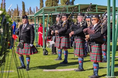 Pipers of the Mesa Caledonia Pipe Band playing in red tartan kilts.